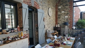 Un espace de restauration extérieur rustique, agrémenté d’un mur en pierre, d’une table en bois et de chaises.
