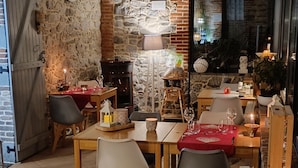 Un coin repas chaleureux avec un mur en pierre, des meubles en bois et une cheminée.