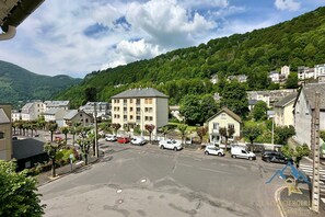 Un estacionamiento con varios autos, rodeado de edificios y un paisaje montañoso.