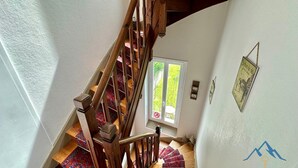 Eine Holztreppe mit gemustertem Teppich, die zu einer Tür mit einem Verbotsschild führt.