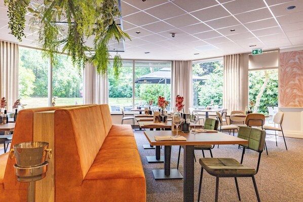 A modern dining area with a wooden bench, tables, chairs, and hanging plants.