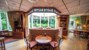 A cozy room with a fireplace, a large window, and a chess table. - Peaceful Getaway — Free Parking, Indoor Pool, and Everything You Need to Unwind (Lochem)
