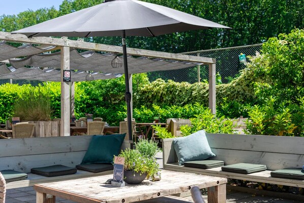 An outdoor seating area with wooden benches and a table under a large umbrella.