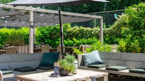 An outdoor seating area with wooden benches and a table under a large umbrella. - Tranquil Countryside Haven w/scenic forest trail, Outdoor adventure & city sites (Bosschenhoofd)
