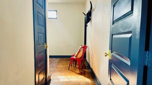 A hallway with wooden flooring, a red chair, and a wall-mounted decorative item. - Historic Store & Basecamp for Fort Davis, Marfa, Alpine and all things Far West (Fort Davis)