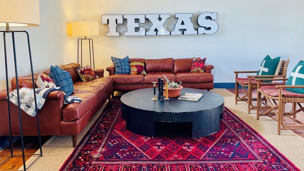 A living room with a sectional sofa, a round coffee table, and a large rug. - Historic Store & Basecamp for Fort Davis, Marfa, Alpine and all things Far West (Fort Davis)