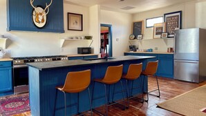 A modern kitchen with a central island, bar stools, a refrigerator, and a mounted deer skull. - Historic Store & Basecamp for Fort Davis, Marfa, Alpine and all things Far West (Fort Davis)