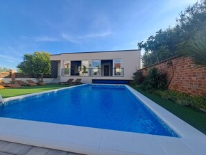 A modern house with a swimming pool, two lounge chairs, and a brick wall. - Villa Nicoletta in Polaca (Polaca)
