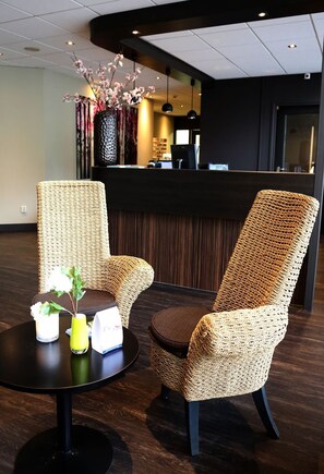 A reception area with wicker chairs, a round table, and a vase with flowers. - Amazing De Bult Getaway w/Balcony | Breathtaking Outdoor Adventure (De Bult)