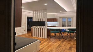 Ein modernes Interieur mit Holzboden, einer weißen Trennwand und einer Essecke mit grünen Stühlen.