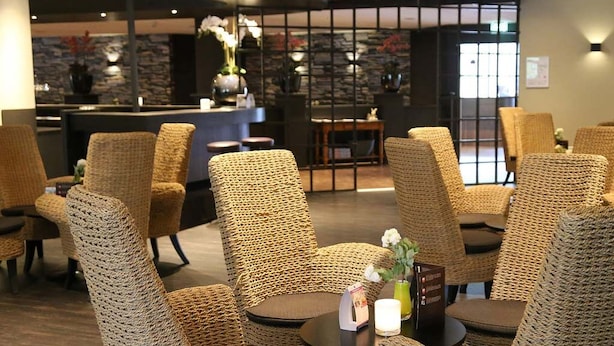A hotel lobby with wicker chairs and tables, a reception desk, and a stone wall.