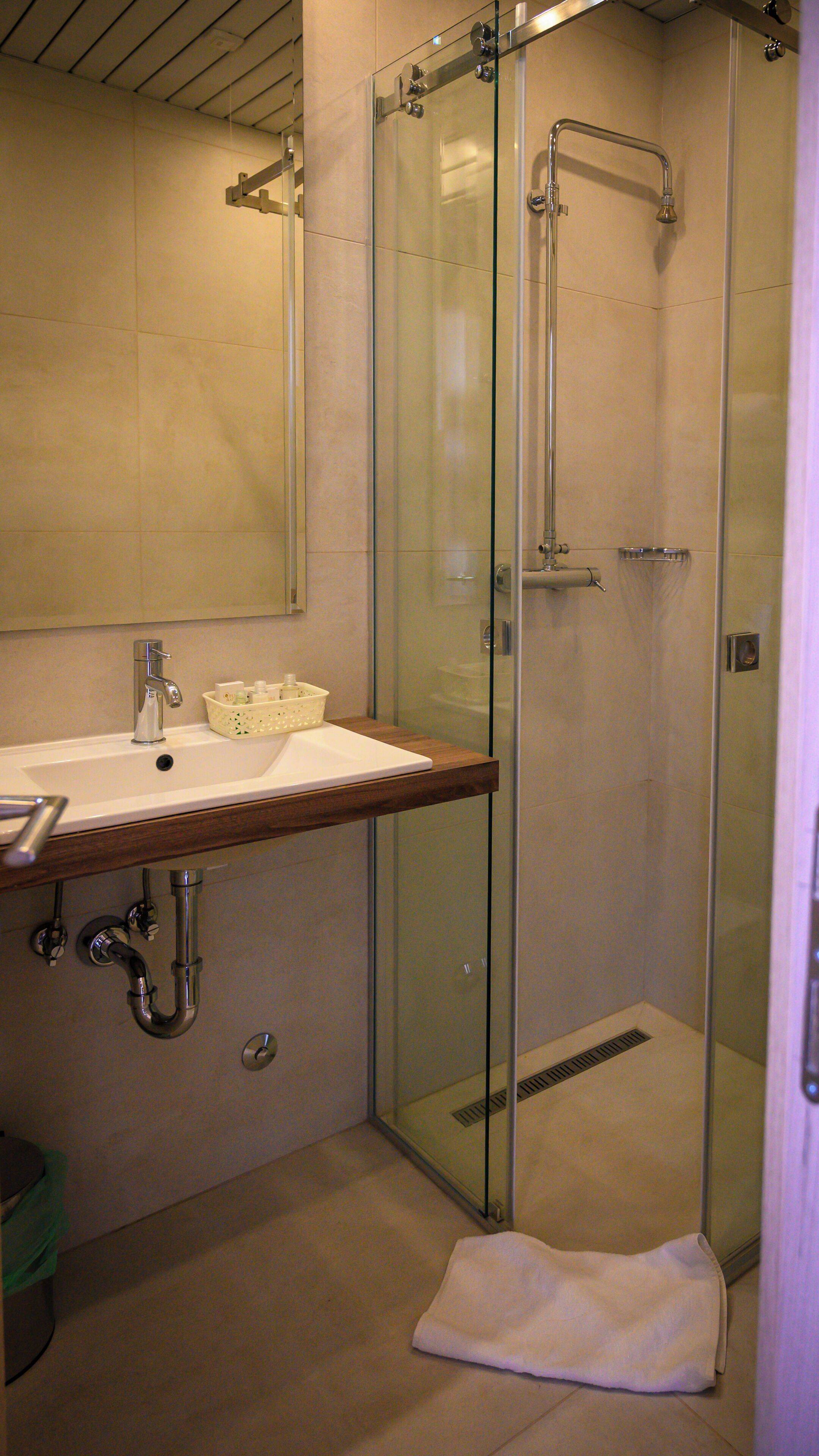 A bathroom with a glass-enclosed shower, a sink with a wooden countertop, and a mirror above the sink.