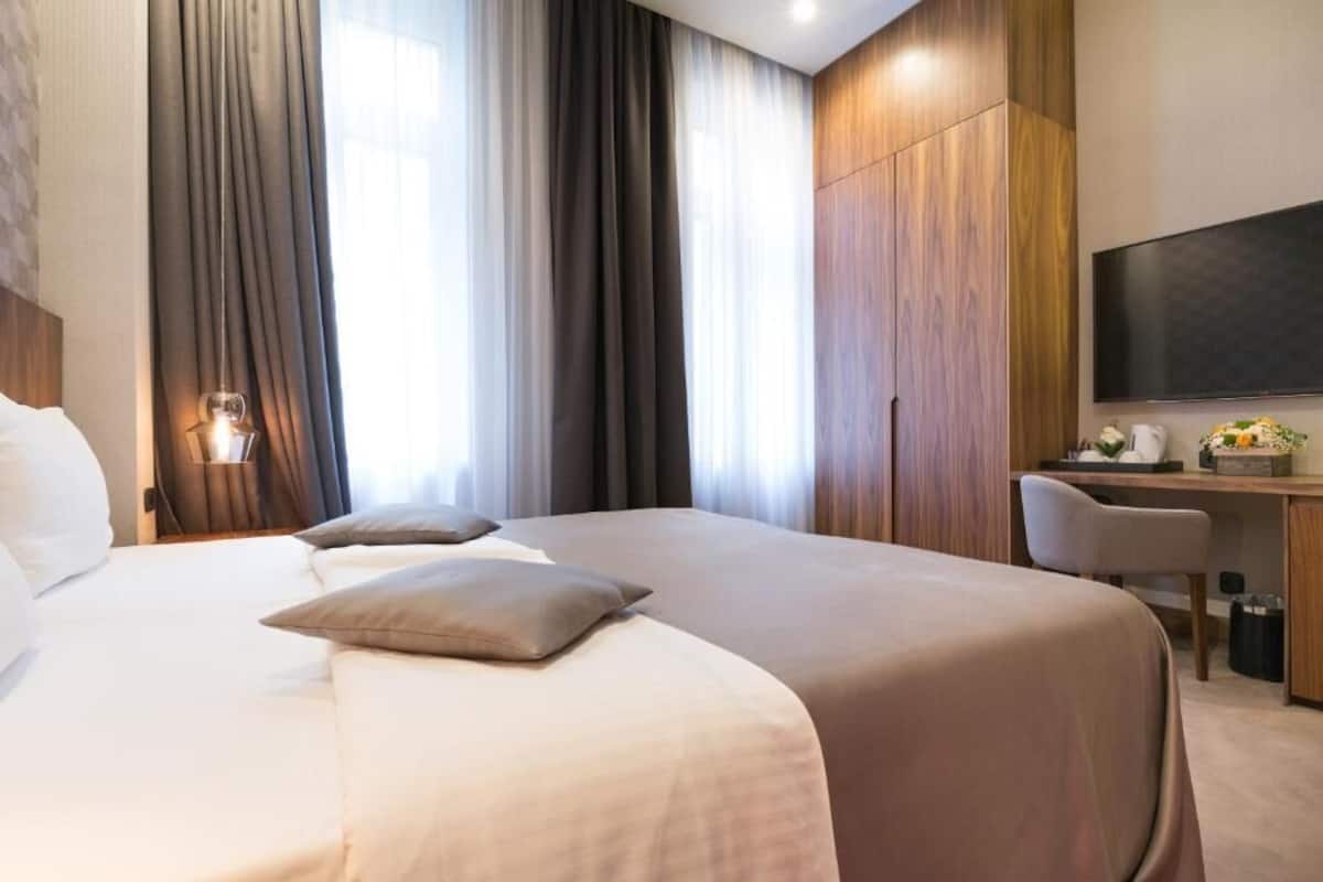 A hotel room with a large bed, a desk, a flat-screen TV, and a wardrobe.