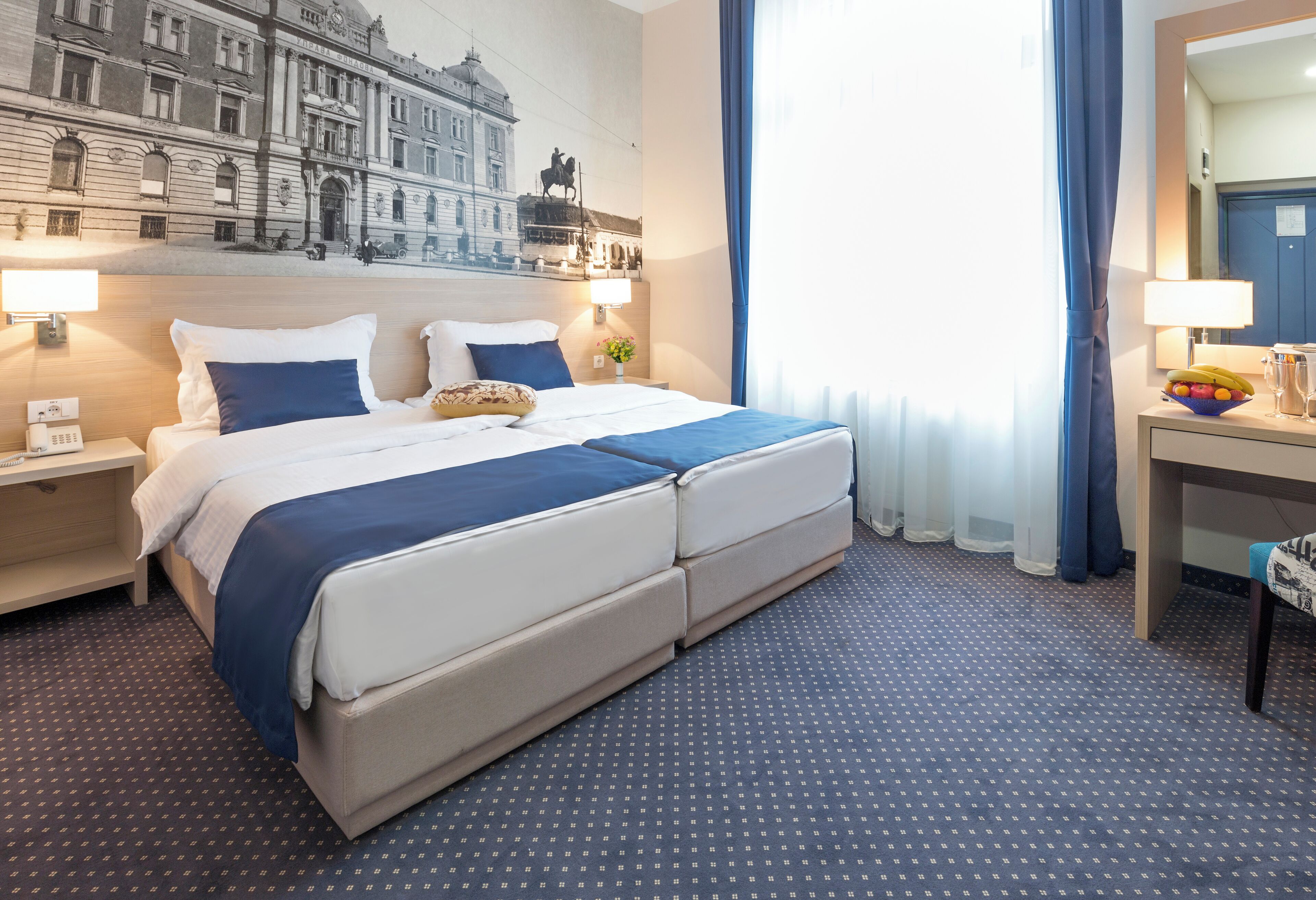 A hotel room with a large bed, two bedside tables, a desk, and a chair.