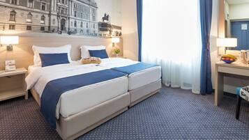 A hotel room with a large bed, two bedside tables, a desk, and a chair.