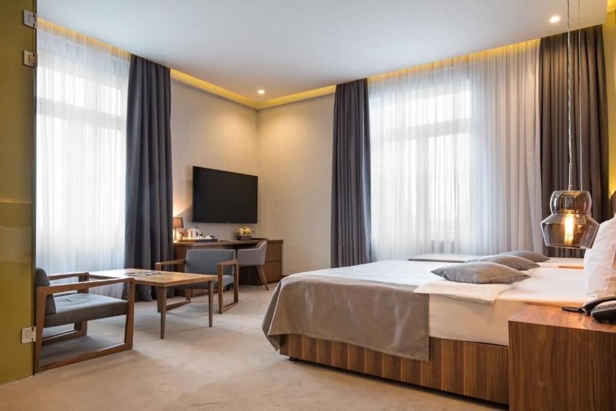 A modern hotel room with a bed, desk, and seating area.