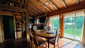 A wooden interior with a dining table, chairs, and a kitchen area. - The Loon Call: Gorgeous Lakefront Family Cottage (Ladysmith)