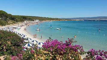 Uma praia com águas azuis cristalinas, guarda-sóis e barcos.