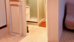 A hallway with a white door leading to a bathroom, a small trash bin, and a sign on the wall. - House 4/5 persons near Puy du Fou (Nueil-les-Aubiers)