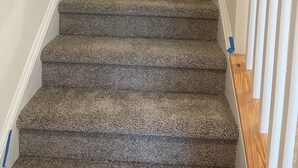 Eine Teppichstiege mit Holnlaufgitter und weißen Wänden.