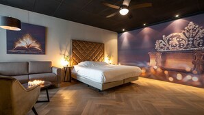 Een moderne slaapkamer met een bed, een slaapbank, een nachtkastje en een wanddecoratie.