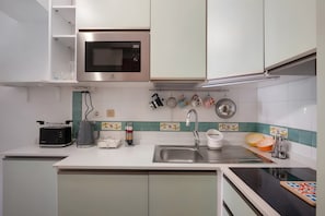 A modern kitchen with a microwave, toaster, kettle, and sink. - Francy's Apartment with Balcony, Wi-Fi and Air Conditioning (Salerno)
