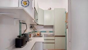 A compact kitchen with white cabinets, a toaster, a kettle, and a small sink. - Francy's Apartment with Balcony, Wi-Fi and Air Conditioning (Salerno)