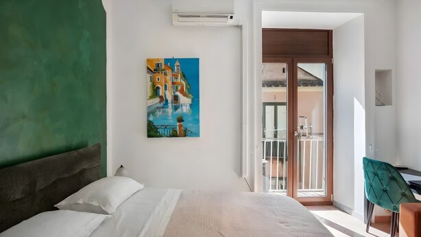 A bedroom with a bed, a painting, a desk, and a chair. - Francy's Apartment with Balcony, Wi-Fi and Air Conditioning (Salerno)
