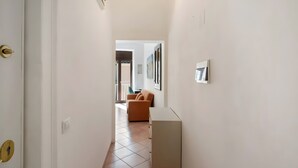 A hallway with a white door, a white cabinet, and a brown sofa in the background. - Francy's Apartment with Balcony, Wi-Fi and Air Conditioning (Salerno)
