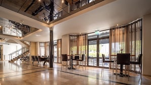 Tilava aula, jossa on korkea katto, suuret ikkunat ja portaikko, joka johtaa ylemmälle tasolle.