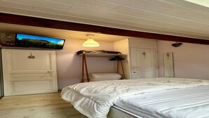 Un dormitorio con una cama, televisor montado en la pared, una lámpara de techo y un armario.