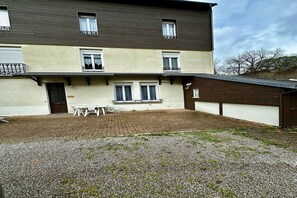 A two-story building with a patio area, a door, and a small table with chairs. - Waterfall View Stay for Family (Mont-Dore)