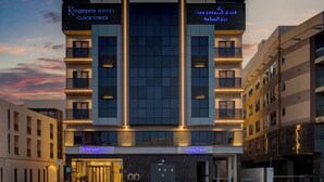 A modern hotel with a prominent clock tower, multiple floors, and illuminated signage. - Kingsgate Hotel Clocktower (Dubai)