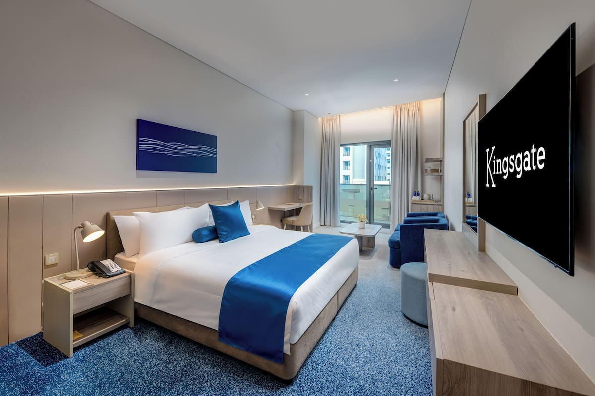Ein modernes Hotelzimmer mit einem großen Bett, Nachttischen, einem Schreibtisch, einem Flachbildfernseher und Blick auf die Stadt.