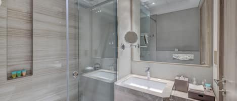 A modern bathroom with a glass shower enclosure, a sink with a marble countertop, and a large mirror.