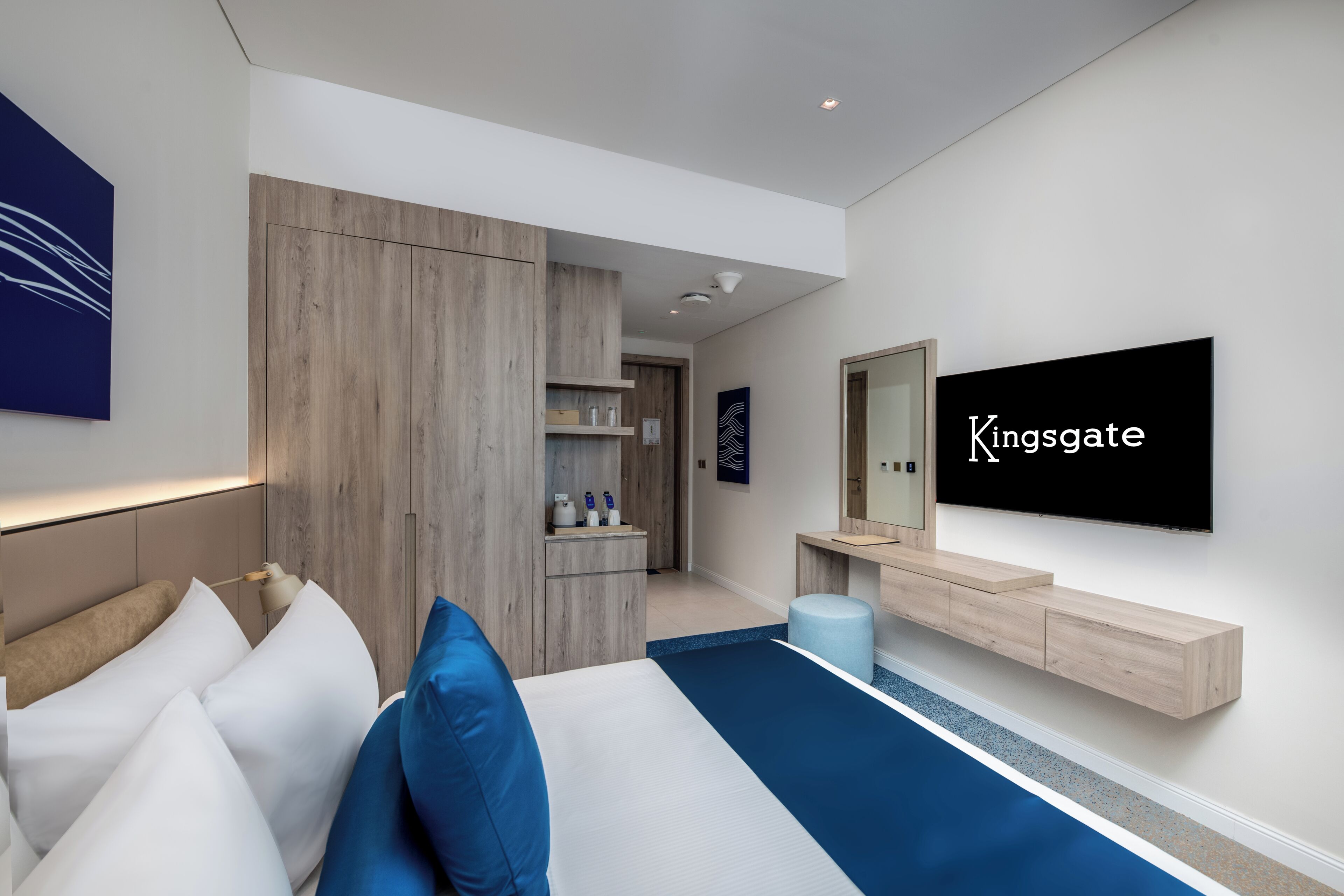 Ein modernes Hotelzimmer mit einem Bett, einem Fernseher, einem Kleiderschrank und einem Badezimmer.