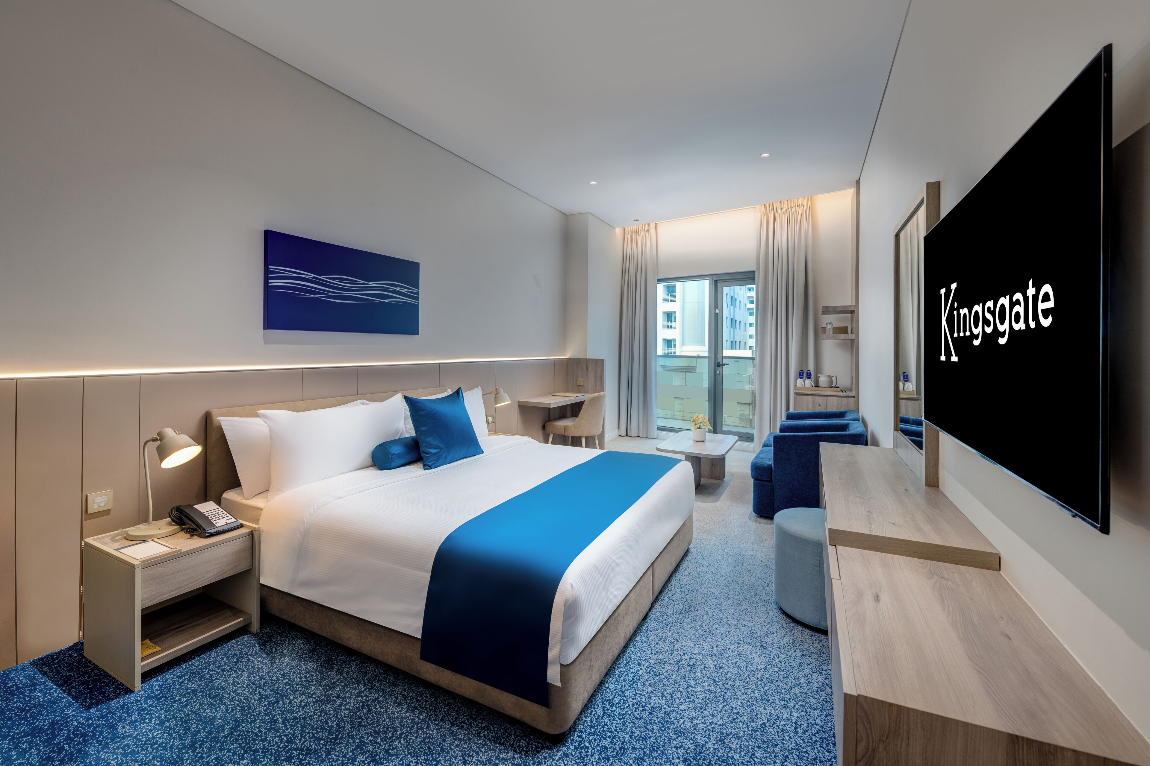 Una camera d'albergo moderna con un letto grande, comodini, una scrivania, una TV a schermo piatto e vista sulla città.