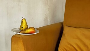 A mustard-colored sofa with a plate of fruit on a side table. - hellofrom Tobacco Warehouse (Kavala)