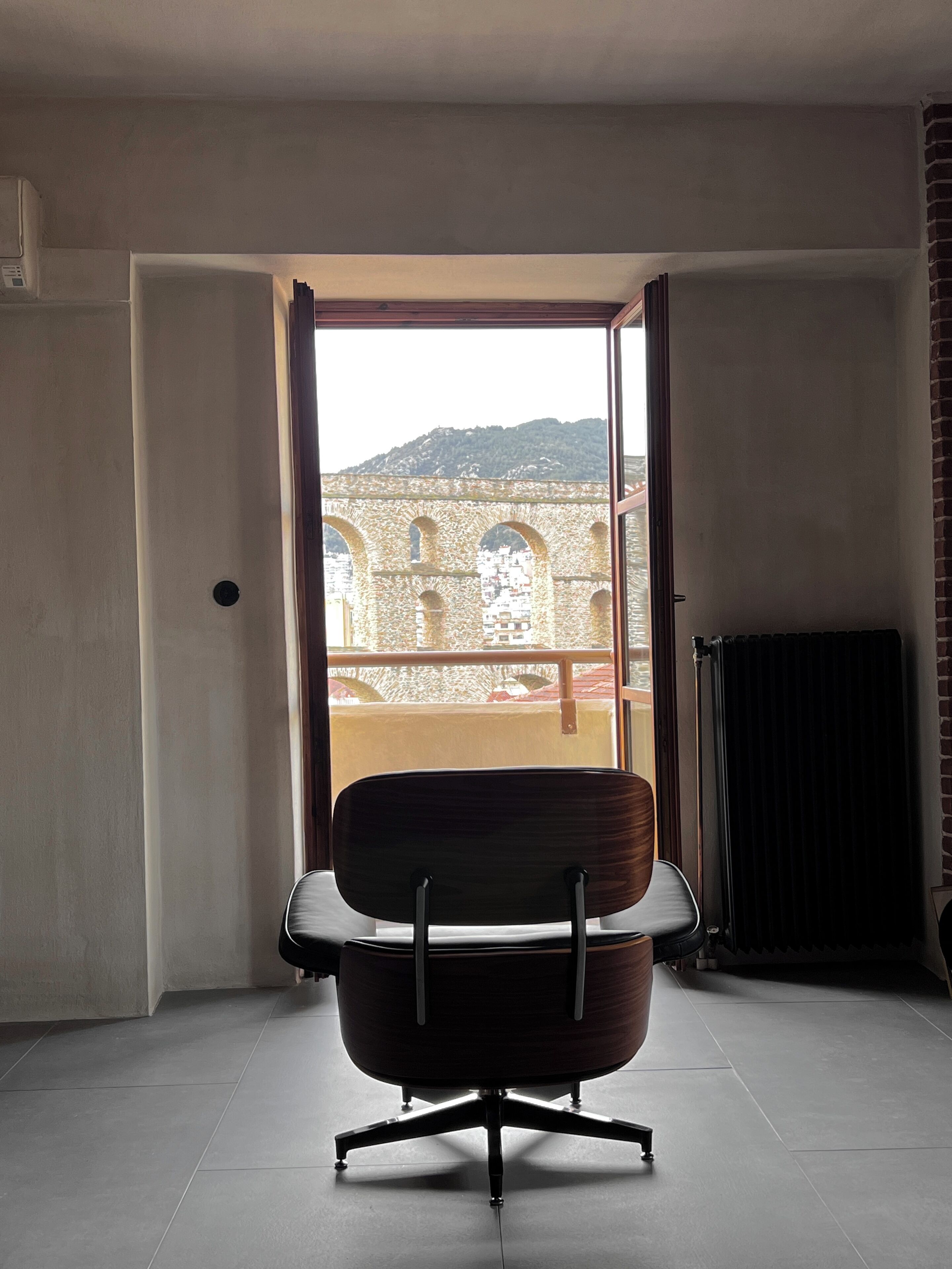Una habitación moderna con un ventanal grande, una silla y un radiador.