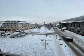 A snow-covered urban area with buildings, a road, and a car. - Bright Apartment in Mont-Dore (Mont-Dore)