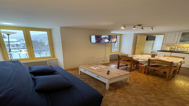 A living room with a sofa, a coffee table, and a TV mounted on the wall. - Bright Apartment in Mont-Dore (Mont-Dore)