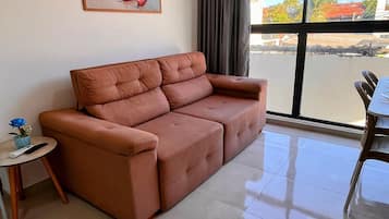 A living room with a sofa, a small table with a vase, and a painting on the wall.