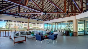 Un amplio salón al aire libre con techo alto, asientos cómodos y ventanas grandes que ofrecen vistas del entorno.