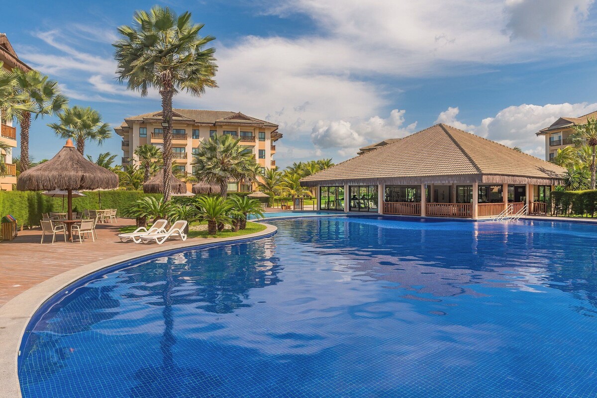 A swimming pool with lounge chairs, palm trees, and a gazebo.