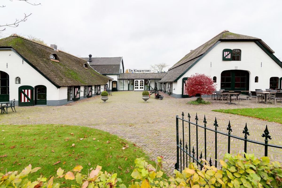 En traditionel bygning med stråtækt tag, en central gårdsplads og udendørs siddepladser.