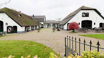 En traditionel bygning med stråtækt tag, en central gårdsplads og udendørs siddepladser.
