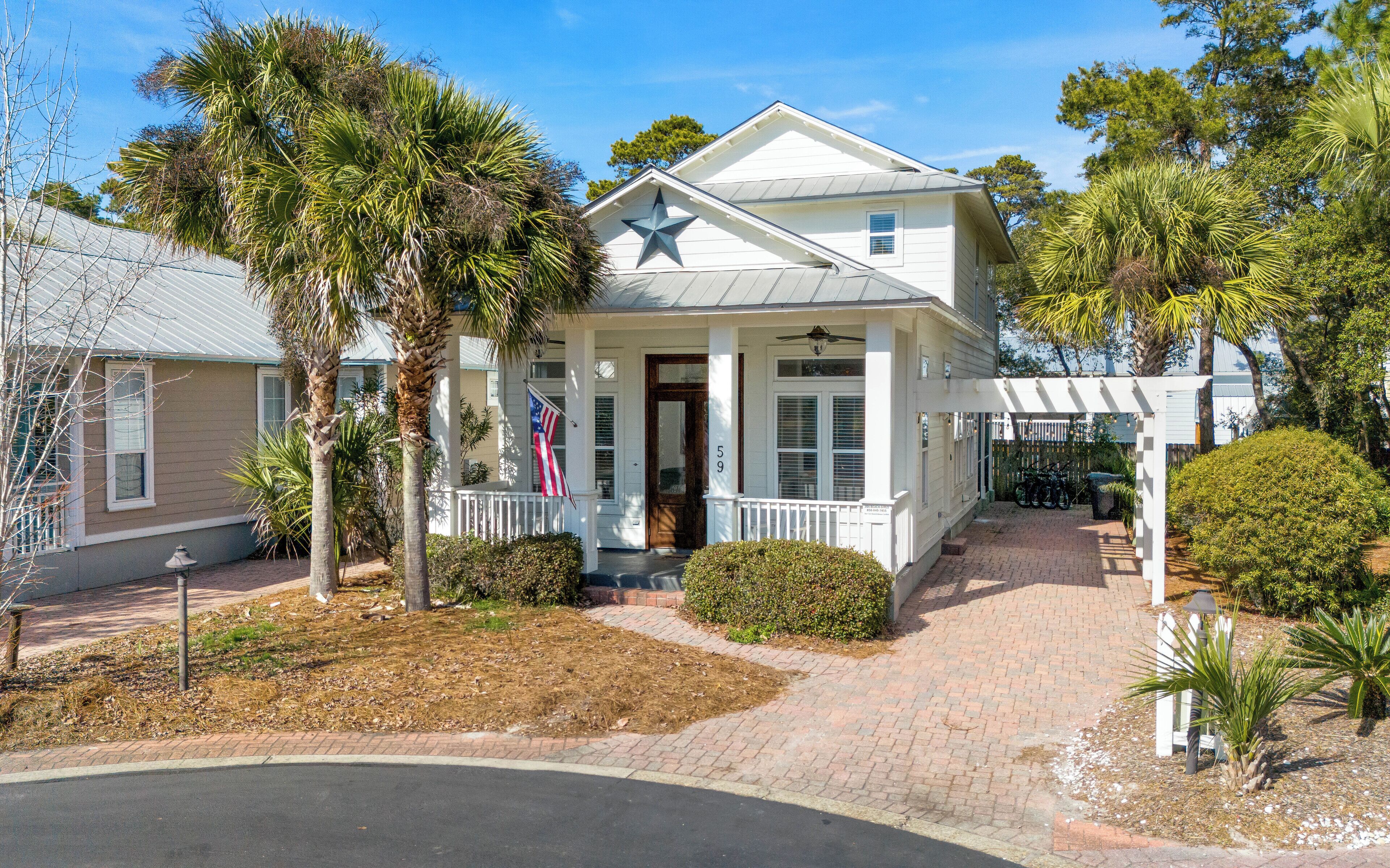 Charming coastal cottage with tropical palm trees and welcoming front porch creates the perfect beachside retreat setting.