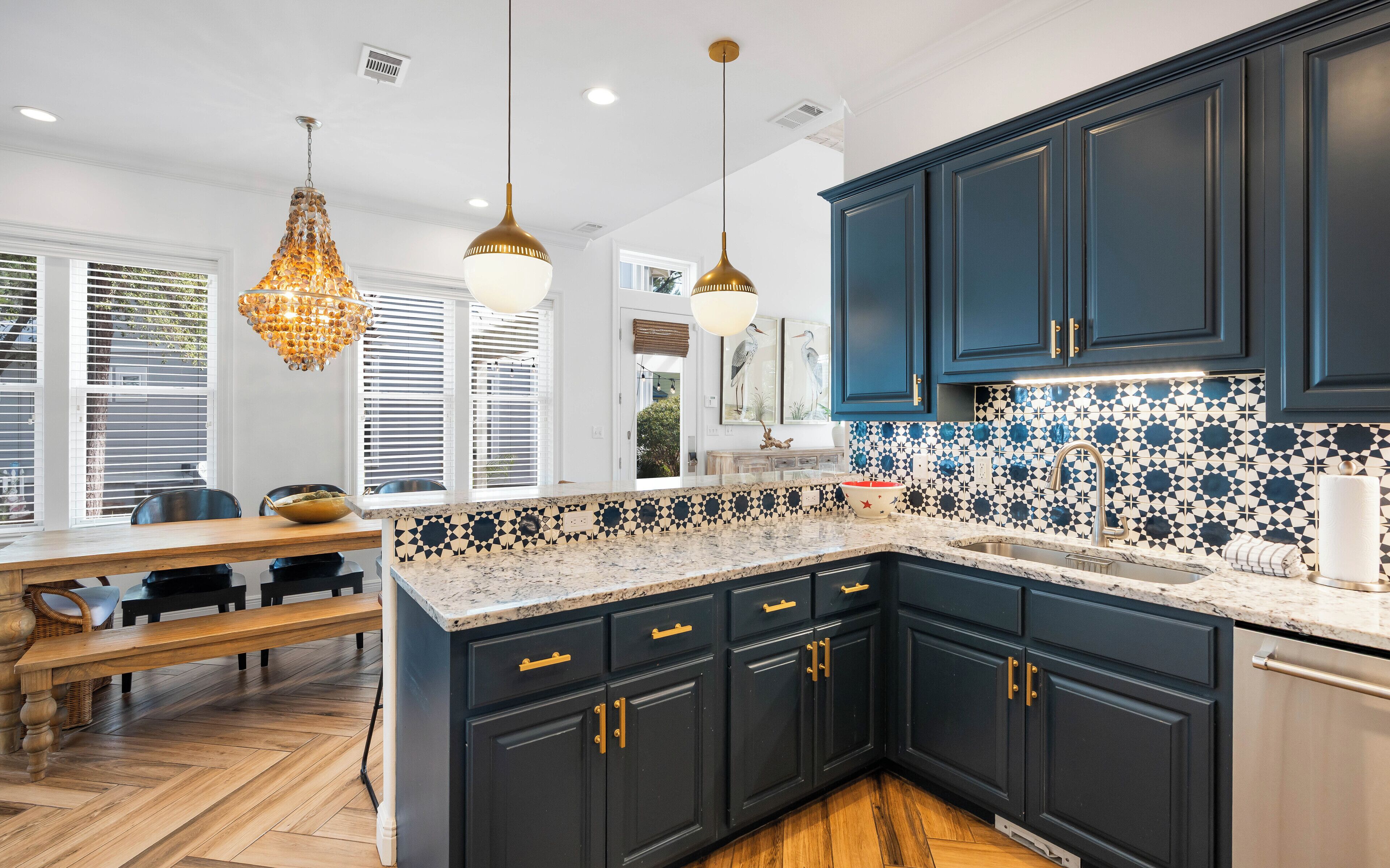 A modern kitchen with dark blue cabinets, a marble countertop, and a patterned backsplash.