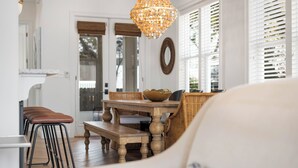 Un coin repas avec une table en bois, des chaises en osier et un lustre suspendu.