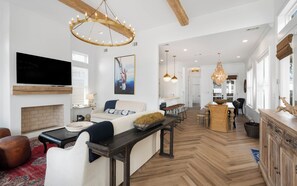 A spacious living room with a fireplace, a large TV, and a dining area with a wooden table and chairs.